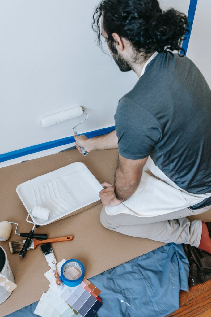 Man painting am interior wall with a small roller brush